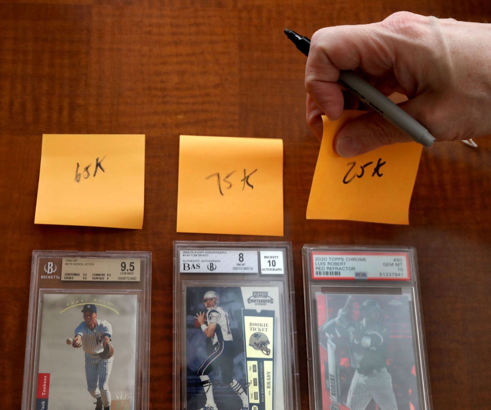 Sports cards of New York Yankees baseball great, Derek Jeter, football legend Tom Brady, and baseball star Luis Robert with prices which Brandon Sommers was hoping for a sale of the cards to fellow collector Anthony Dovine.